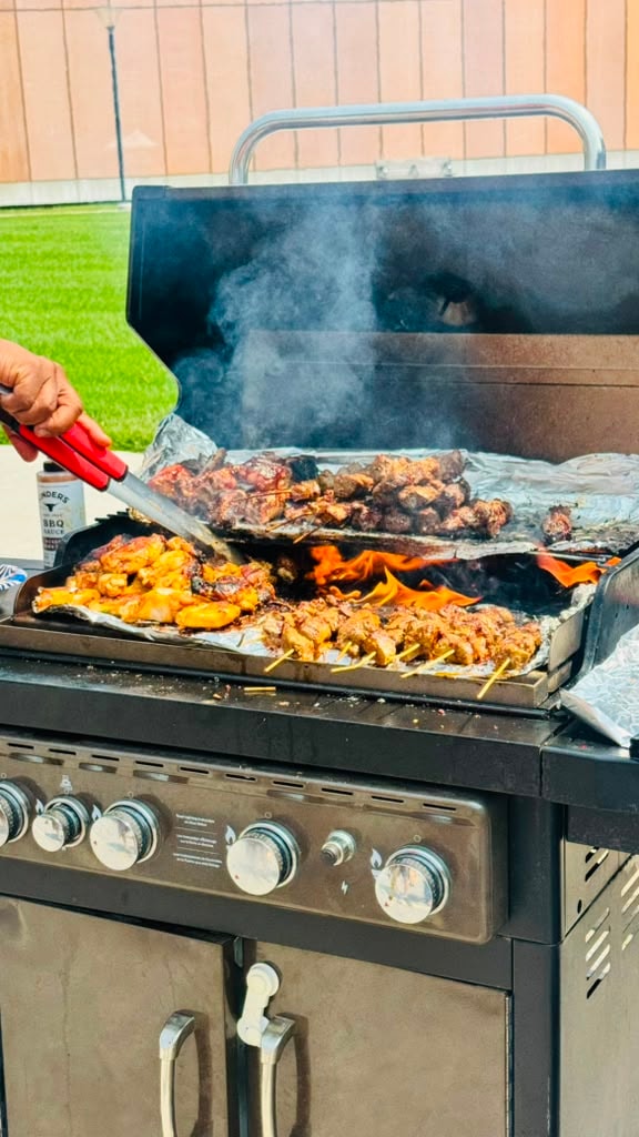 Sizzling African BBQ skewers and grilled meats cooking on a large outdoor grill