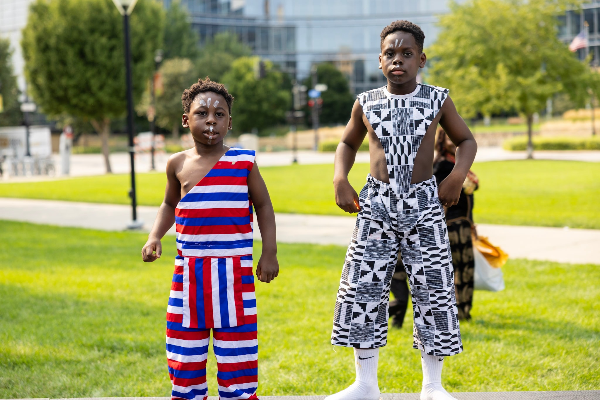 Two young boys in traditional kente and striped attire posing at the festival