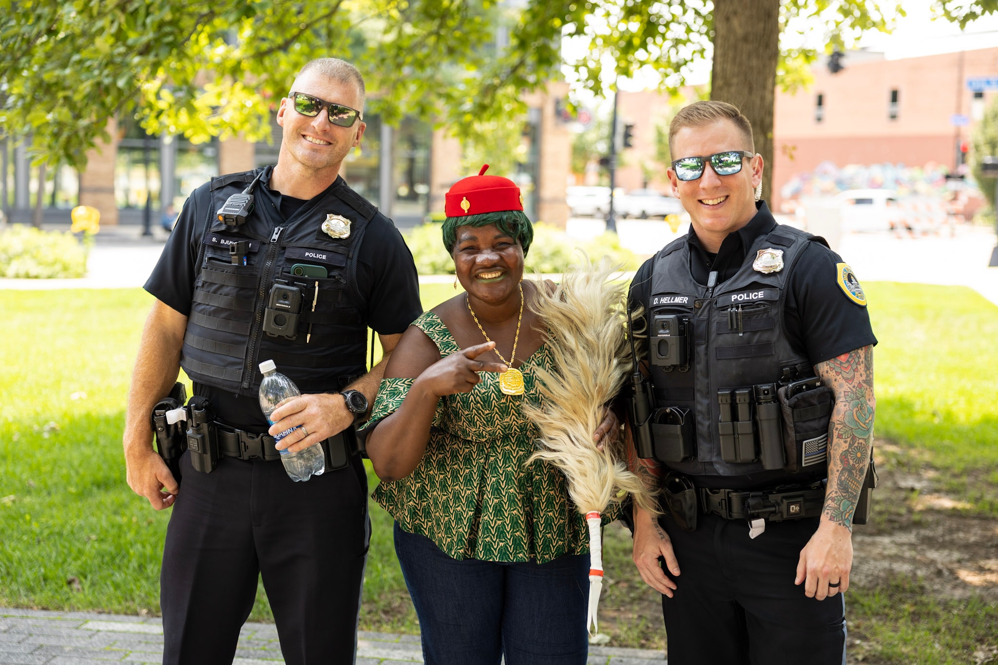 Festival attendee in traditional green attire smiling with two Des Moines police officers