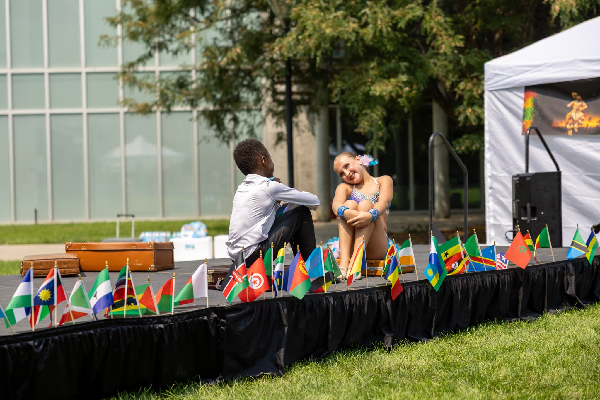 Young boy and girl sitting together on stage between performances with African flags lining the front