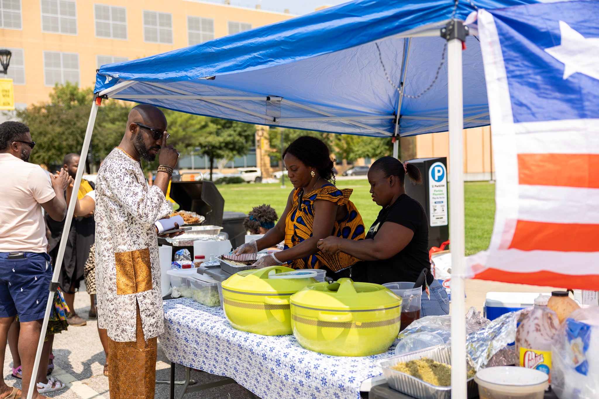 Attendees being served food at a booth with the Liberian flag in the background
