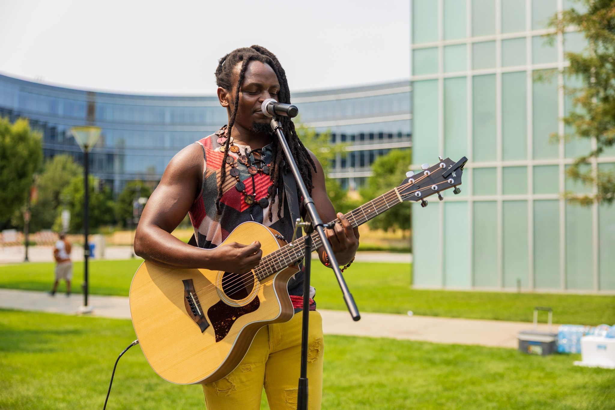 Musician with dreadlocks playing acoustic guitar and singing at the outdoor festival stage