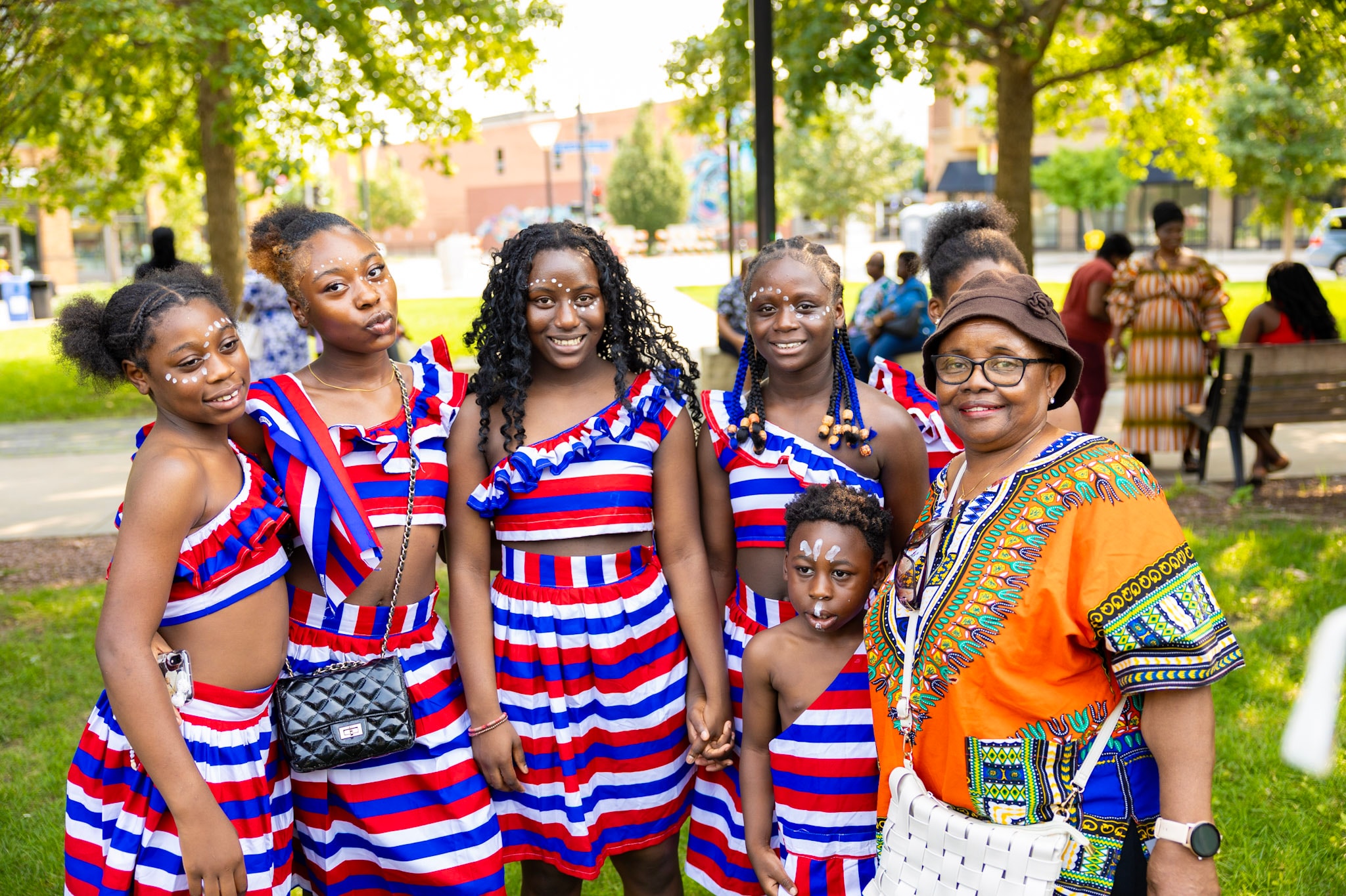 Group of young dancers in striped outfits posing with an elder after their performance