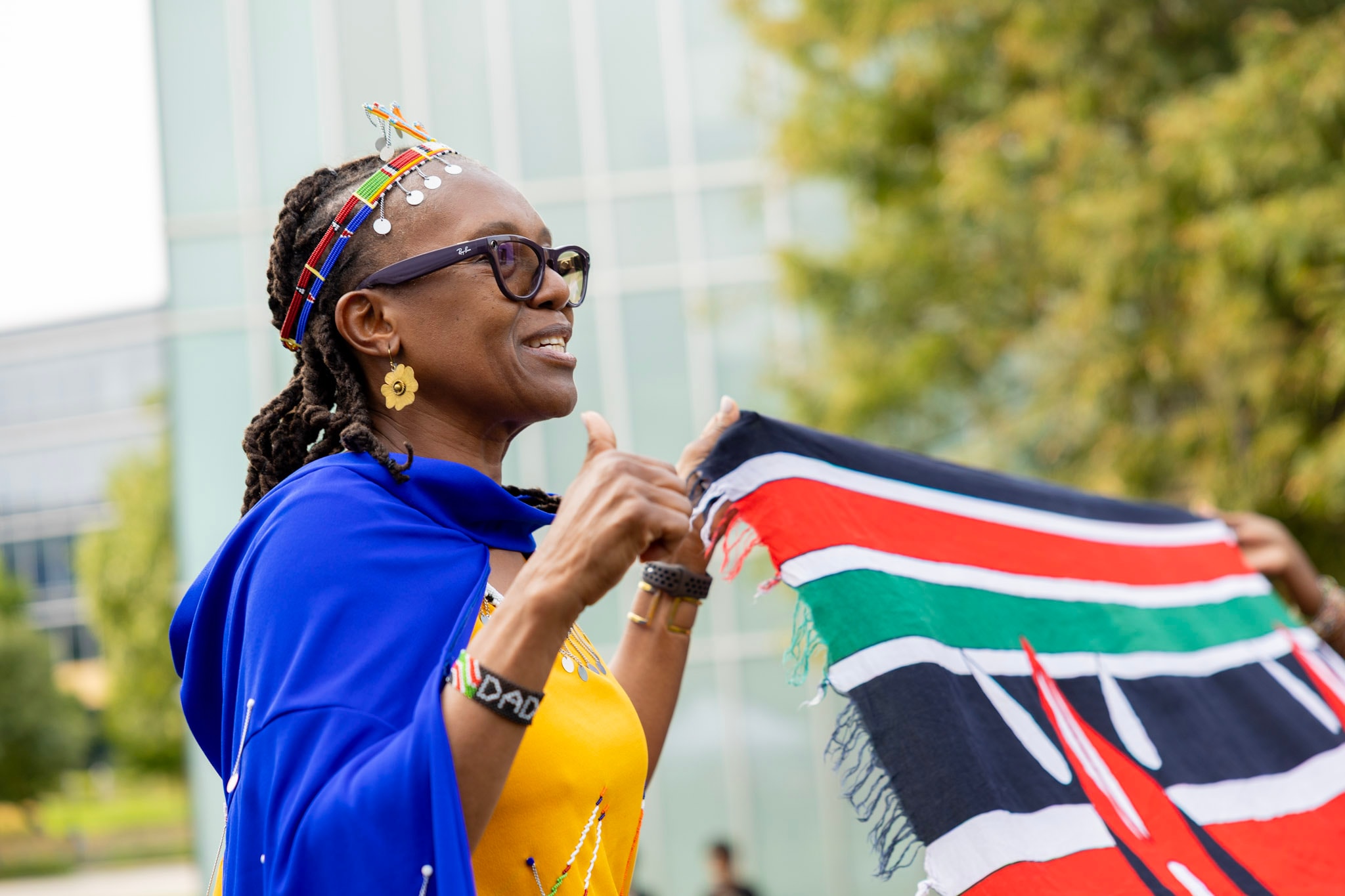 Woman in traditional Maasai beaded headpiece joyfully waving the Kenyan flag