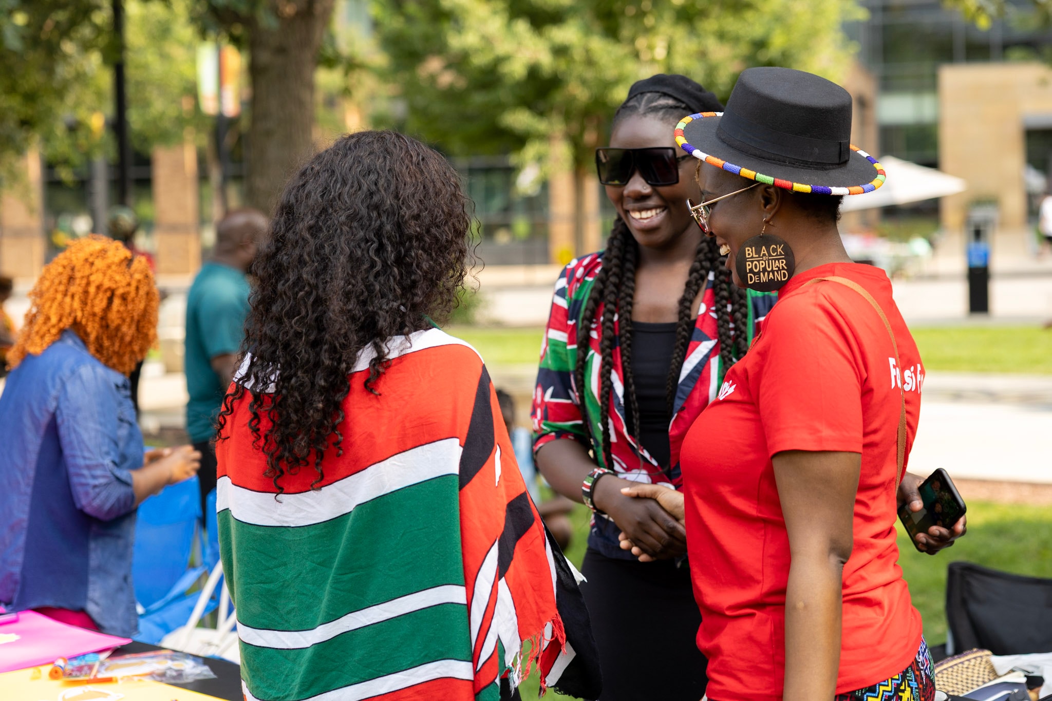 Three women laughing together wearing Kenyan flag wraps at the festival